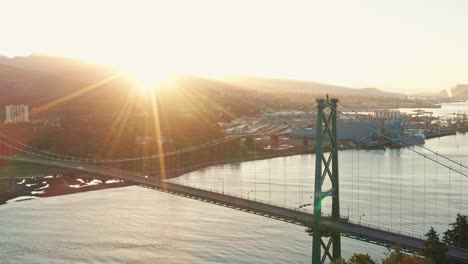Picturesque-Aerial-Drone-Shot-Flying-towards-the-Lions-Gate-Bridge-and-Into-the-Sun-in-Vancouver