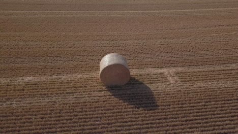 Orbiting-aerial-of-morning-sun-on-golden-hay-bale-in-freshly-cut-field