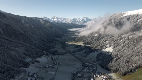 Aerial-view-of-a-mountain-valley-during-sunrise-covered-with-the-first-snow-of-the-season