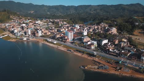 Drone-aerial-revealing-shot-of-town-near-the-lake-in-El-Peñón-in-Guatapé,-Colombia