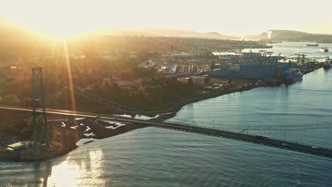 Drohnenkippluftaufnahme-Mit-Der-Sonne,-Die-über-Der-Lions-Gate-Bridge-Vor-Dem-Hafen-Von-Vancouver-Aufgeht