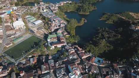 Drone-aerial-view-of-the-city-in-Guatapé-revealing-the-lake-at-El-Peñón,-Colombia
