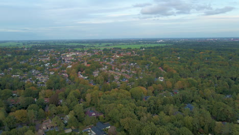 Aerial-of-small-town-surrounded-by-beautiful-forests-in-autumn