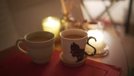 Two-Cups-Of-Hot-Beverage-With-Candlelights-On-The-Table---close-up