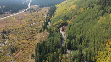 Colorado-USA,-Countryside-in-Autumn,-Yellow-Green-Landscape,-Forest-and-Creek-in-Valley,-House-and-Road,-Drone-Aerial-View