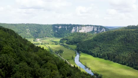 Aerial-View-of-Idyllic-Valley-next-to-Green-Forest-in-Hilly-Landscape