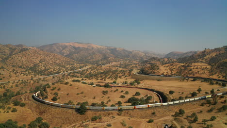 As-one-train-sits-idle-on-the-tracks-another-train-climbs-the-Tehachapi-loop---aerial-view