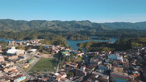 Drone-aerial-rising-shot-of-town-in-Guatapé-revealing-the-lake-in-Medellin,-colombia