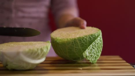 Close-up-shot-of-woman's-hands-slicing-a-savoy-cabbage-in-half-before-cooking