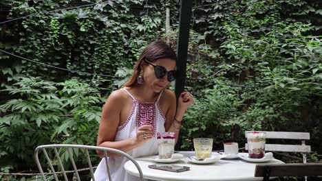 Girl-Tasting-Fruit-And-Yoghurt-Parfait-And-Checking-Phone-In-A-Cafe-Looking-Chic