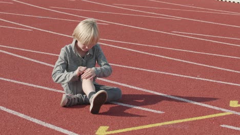 Blond-boy-fell-down-on-running-track-and-injured-his-knee