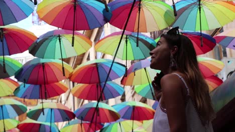 Mädchen,-Das-Farbige-Regenschirme-Aufschaut-Und-Am-Telefon-Spricht,-Glückliche-Zeitlupe