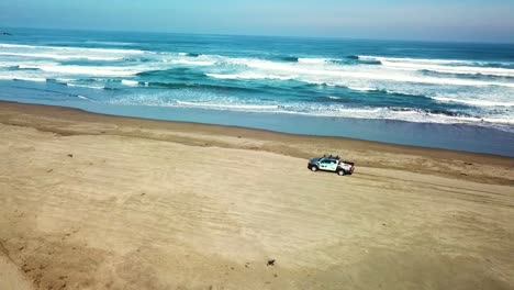Truck-driving-on-beach-next-to-ocean