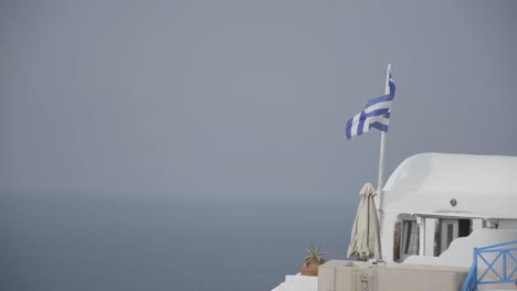 Die-Griechische-Flagge-Weht-Im-Wind-In-Oia-Auf-Der-Insel-Santorini-Griechenland
