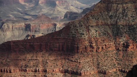 A-long-pan-of-the-Grand-Canyon,-with-the-shadows-of-clouds-on-the-surface-of-the-rock