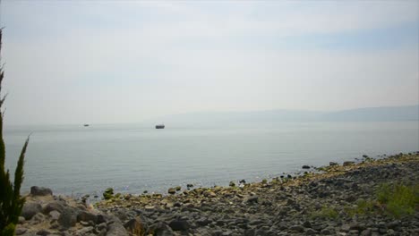 A-recreation-of-a-2000-year-old-boat-sails-across-the-Sea-of-Galilee-in-Israel,-viewed-from-the-shoreline