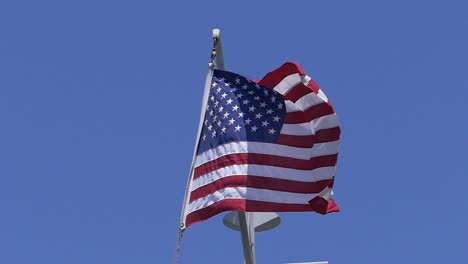 Toma-En-Cámara-Lenta-De-Una-Bandera-Estadounidense-Con-Un-Cielo-Azul-Perfecto-Como-Fondo