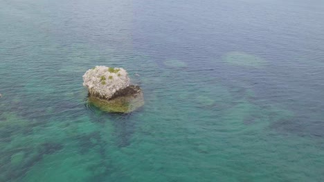 Inward-rotating-drone-footage-of-rock-formation-surrounded-by-shallow-seas-off-the-coast-of-Greece-Kefalonia