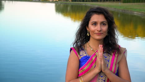 Woman-in-traditional-sari-praying-with-lake-behind