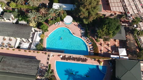 Aerial-drone-shot-of-hotel-gardens-and-swimming-pools-at-a-sunny-resort