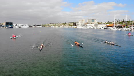 3-crew-rowing-boats-in-regatta-race-in-Newport-Harbor,-California,-aerial-drone-overhead-dolly