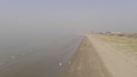 Aerial-trucking-shot-of-sandy-coastline-in-Nature-Reserve-Dunes-of-Koksijde-Oostduinkerke-and-Nieuwpoort-City-in-background