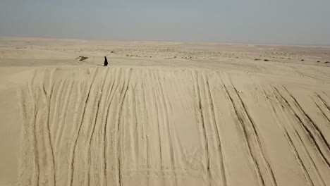 Woman-walking-on-sand-dune-wearing-black-abaya