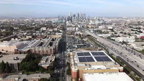 Aerial-forward-view-of-highway-to-Los-Angeles-metropolis-and-skyline,-USA