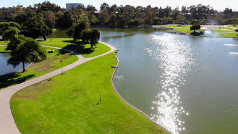Pull-Fly-back-from-beautiful-lake-Mason-Regional-Park-in-Irvine,-California-Orange-County-suburban-park-its-aerial-4k-DJI-drone