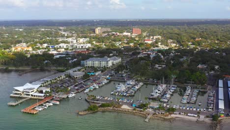 Drone-footage-over-downtown-Dunedin,-Florida-marina-with-boats-and-the-Gulf-of-Mexico-and-Tampa-Bay