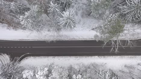 Drohnen-Luftaufnahme-Eines-Verschneiten-Waldes-Und-Einer-Landstraße-Im-Landkreis-Kaunas,-Litauen
