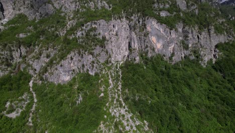 Climbing-mountain-slope-with-steep-cliffs-and-green-trees,-beautiful-mount-texture-in-Alps