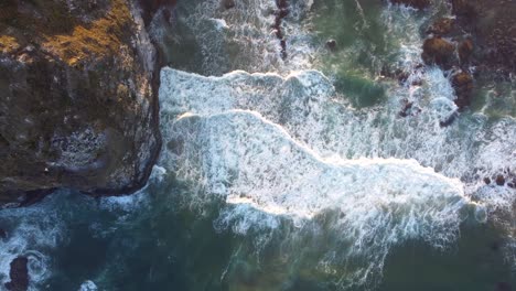 Beautiful-Sunrise-on-the-Oregon-Coast---Mossy-Haystack-Rock-and-Crystal-Clear-Blue-Water-Crashing-Against-the-Pacific-Ocean-Coast,-Sea-birds-flying-above-4K-30fps-Aerial-Drone-Footage-Straight-Down