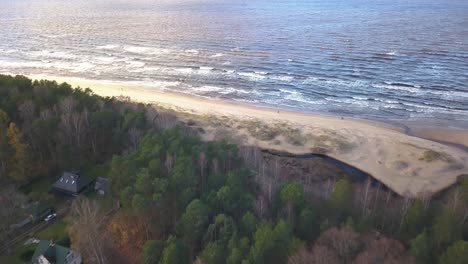 Aerial-shot-of-a-beautiful-beach-during-golden-hour,-sun-light-reflected-on-the-water