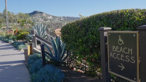 Camera-pan-of-a-beach-access-sign,-along-a-walking-path,-in-Laguna-Beach-California