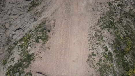 Aerial-shot-of-two-dirt-bike-riders-going-under-camera,-panning-straight-down