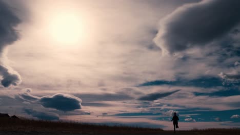 Striking-black-silhouette-outline-of-a-female-jogger,-jogging-against-a-dramatic-sky
