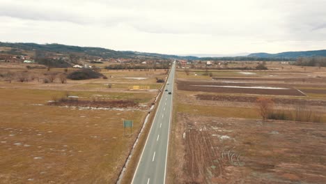 Coches-En-La-Carretera-Entre-Tierra-Cultivable,-Drone-4k-De-Color
