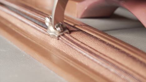 Opening-zipper-of-brown-and-grey-suitcase,-Extreme-Close-Up