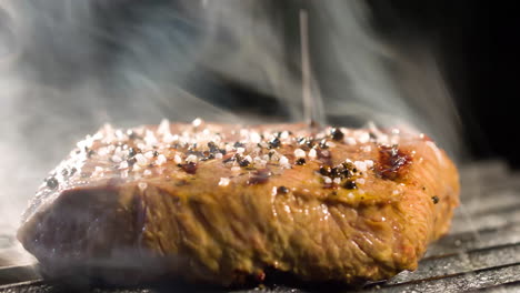 Großes-Steak-Wird-Gegrillt,-Es-Gibt-Rauch-Von-Den-Kohlen-Zum-Fleisch,-Seitenansicht,-Nahaufnahme-4kSteaksteak-Mit-Einer-Sehr-Leckeren-Aussicht-4k