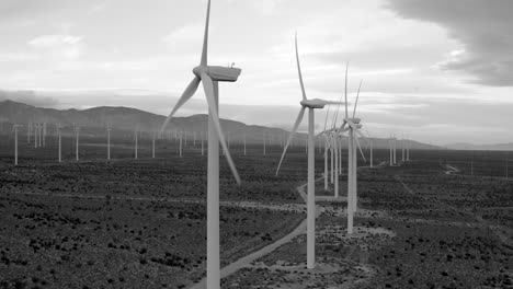 Aerial-rising-wind-turbines,-renewable-energy-global-warming-climate-change,-black-and-white