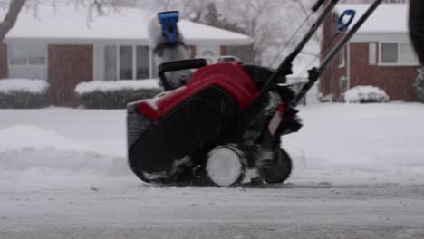 Close-Up-of-Snowblower-Clearing-Snow-from-Driveway-on-a-Snowy-Day