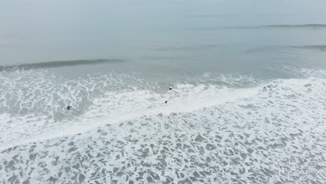 Three-people-paddling-and-body-surfing-in-foaming-white-water,-aerial