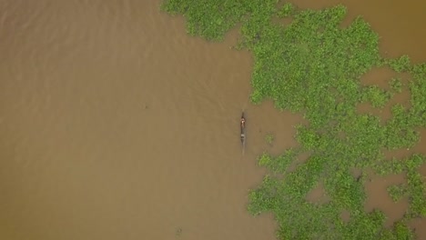 Aerial-view-of-a-small-indigenous-canoe-crossing-a-mound-of-floating-algae-in-the-Orinoco-River