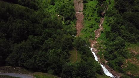 Aerial-view-of-Walcherfall-waterfall,-Ferleiten,-Austria,-flowing-down-near-a-mountain-trail-road