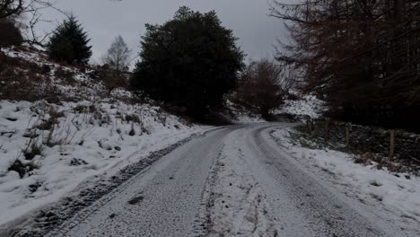 Driving-snowy-empty-rural-country-road-in-slippery-winter-conditions-on-frosty-morning