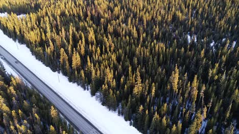 Aerial-View-of-Black-Car-Moving-on-Straight-Road-in-Mountains-Winter-Landscape