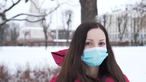 Eine-Einsame-Frau-Mit-Gesichtsmaske-Atmet-Tief-Ein,-Während-Sie-Im-Winter-Im-Stadtpark-Ist