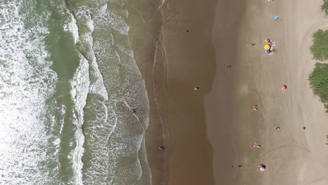 Top-Down-Aerial-View-of-Ocean-Waves-Breaking-on-Sandy-Beach-on-Sunny-Summer-Day