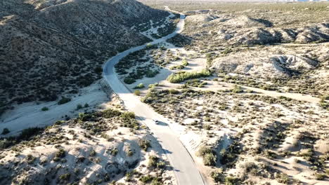 Aerial-Shot-Of-A-Car-Driving-Through-The-Desert-Of-Joshua-Tree-National-Park,-USA